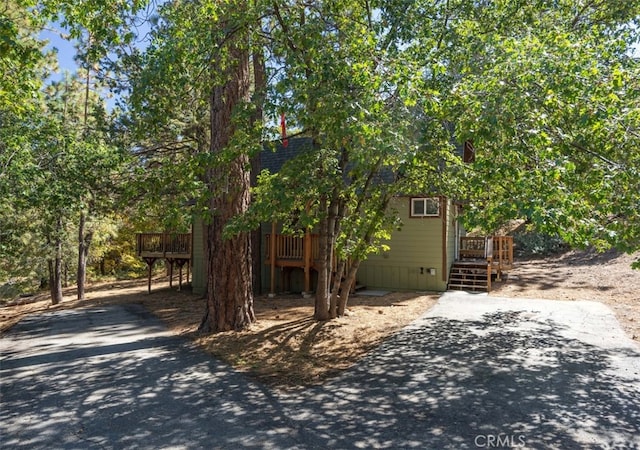 view of property hidden behind natural elements featuring a wooden deck