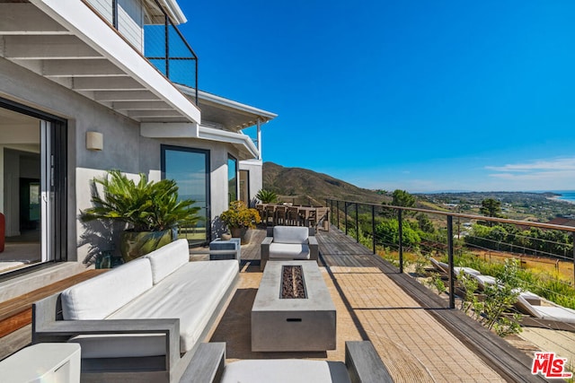 view of patio / terrace featuring a mountain view, a balcony, and an outdoor living space with a fire pit