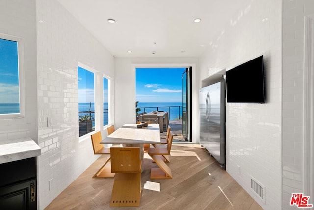 dining space with light wood-type flooring and brick wall