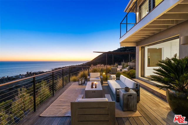 deck at dusk with a water view and outdoor lounge area