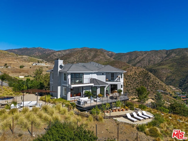 rear view of property featuring a balcony and a mountain view