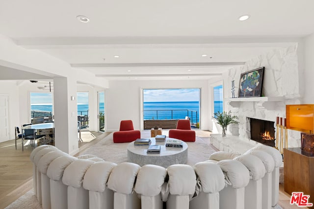 living room with a water view, beam ceiling, a high end fireplace, and light wood-type flooring