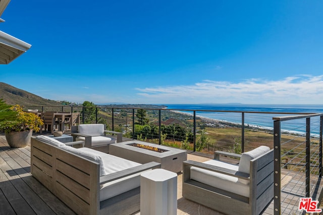 deck featuring a water view and an outdoor living space with a fire pit