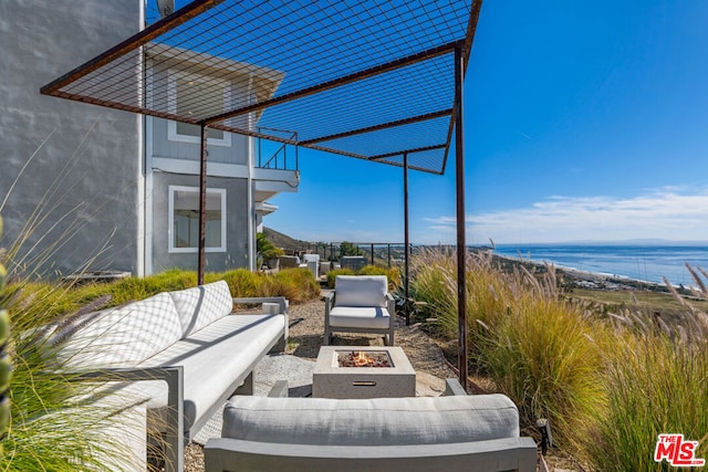 view of patio / terrace with a balcony, a water view, and an outdoor living space with a fire pit