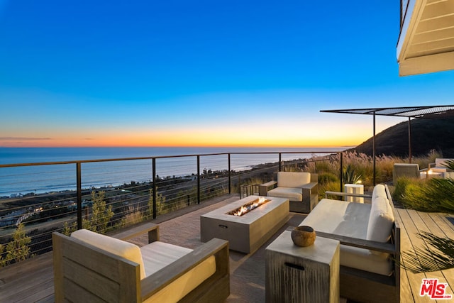 patio terrace at dusk with a water view and an outdoor fire pit