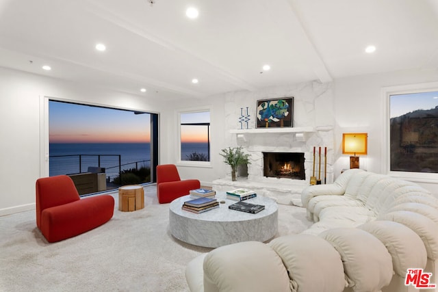 carpeted living room with beam ceiling, a water view, and a premium fireplace