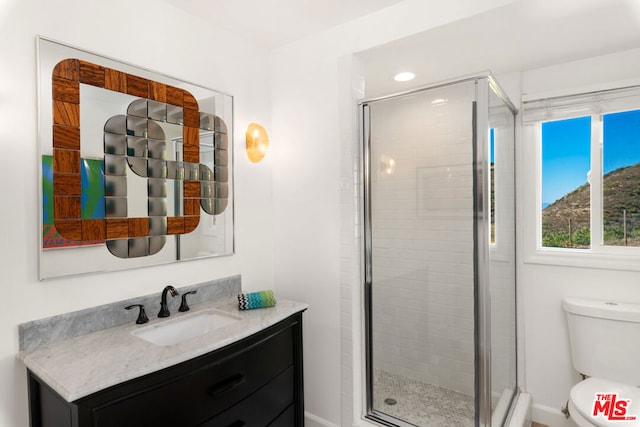 bathroom with walk in shower, vanity, and toilet