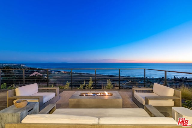 patio terrace at dusk with a water view and an outdoor fire pit