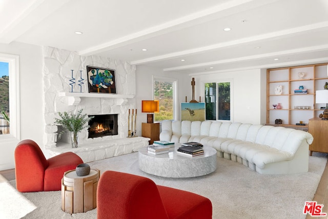 living room featuring a stone fireplace and beamed ceiling