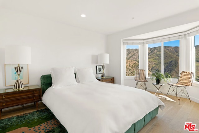 bedroom with light wood-type flooring and a mountain view