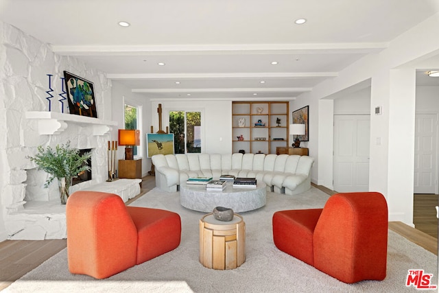 living room with light hardwood / wood-style floors, a fireplace, and beam ceiling