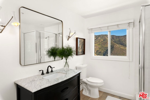 bathroom with hardwood / wood-style flooring, vanity, toilet, and a shower with door