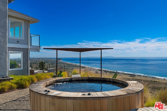 view of pool featuring a view of the beach, a water view, and a hot tub