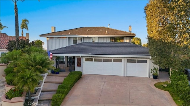 traditional-style house featuring an attached garage, driveway, and a tile roof