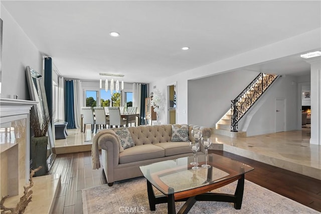 living area featuring stairs, a premium fireplace, wood finished floors, and recessed lighting