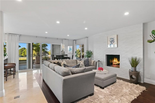 living room with a healthy amount of sunlight, a warm lit fireplace, and recessed lighting