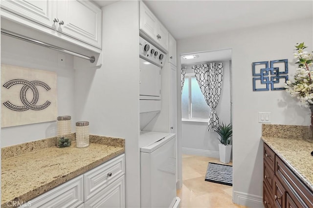 washroom featuring laundry area, stacked washing maching and dryer, and baseboards