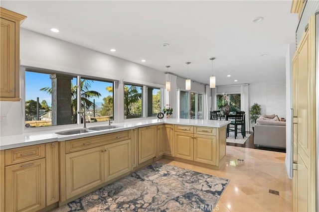 kitchen featuring pendant lighting, recessed lighting, light countertops, open floor plan, and a sink