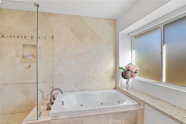 bathroom featuring tile walls, a tile shower, and a jetted tub