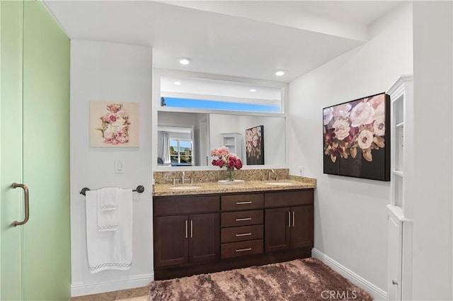 full bathroom featuring double vanity, recessed lighting, a sink, and baseboards