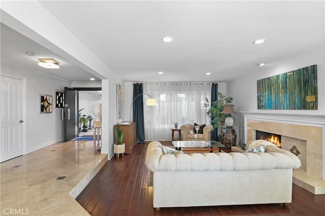 living room with a warm lit fireplace, crown molding, wood finished floors, and recessed lighting