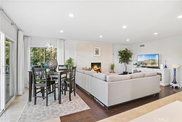 living area with a large fireplace, wood finished floors, visible vents, and recessed lighting