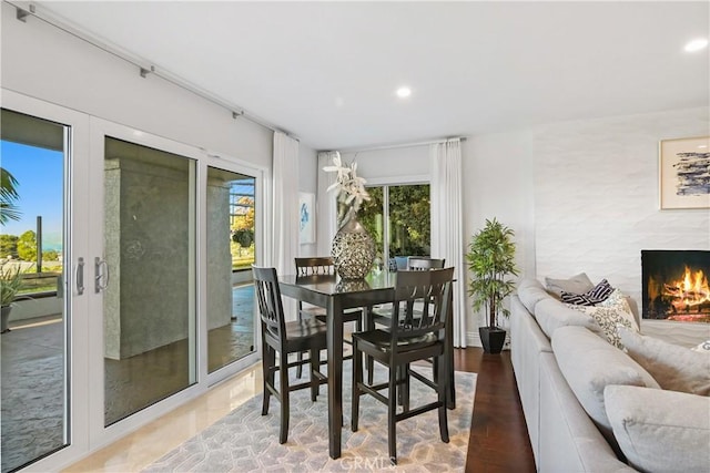 dining area featuring french doors, a premium fireplace, recessed lighting, and a healthy amount of sunlight