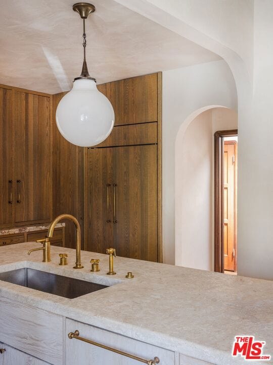 kitchen with wooden walls, sink, and decorative light fixtures