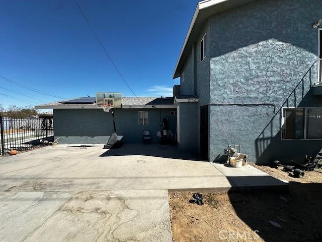 view of side of property featuring fence, solar panels, and stucco siding