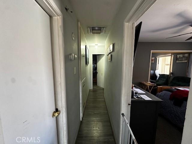 corridor featuring attic access, wood finished floors, and visible vents