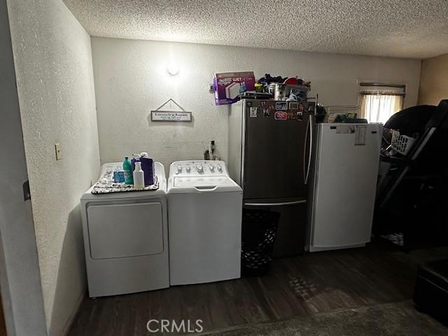clothes washing area with washing machine and clothes dryer, dark wood-style floors, and a textured ceiling