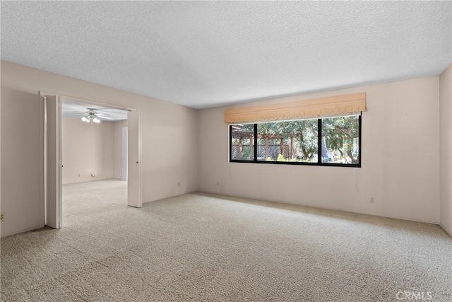 unfurnished room featuring ceiling fan, light colored carpet, and a textured ceiling