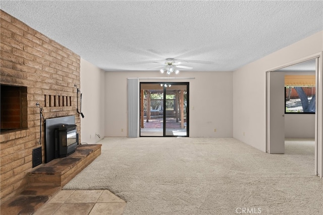 living room with ceiling fan, light colored carpet, a textured ceiling, and a fireplace