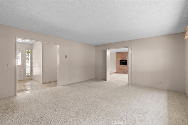 unfurnished room featuring a textured ceiling, a fireplace, and light colored carpet