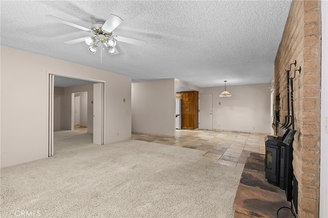 unfurnished living room featuring a textured ceiling, light carpet, ceiling fan, and a wood stove