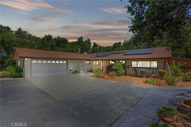 single story home featuring solar panels and a garage