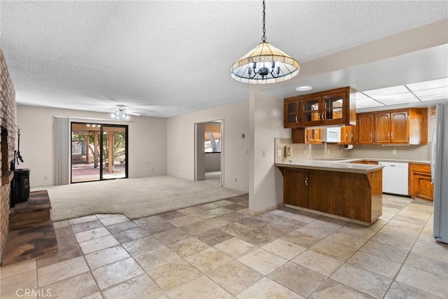 kitchen featuring a kitchen breakfast bar, ceiling fan with notable chandelier, white appliances, kitchen peninsula, and pendant lighting