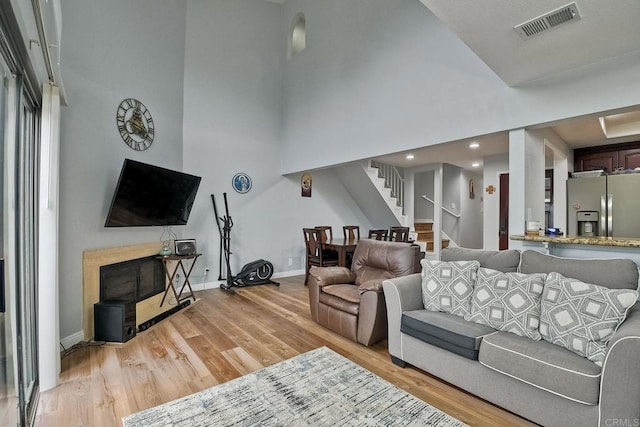 living room with a high ceiling and light hardwood / wood-style flooring