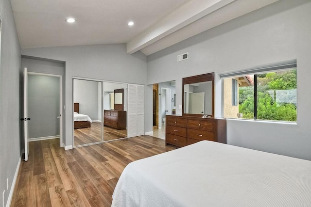 bedroom with a closet, hardwood / wood-style floors, and lofted ceiling with beams