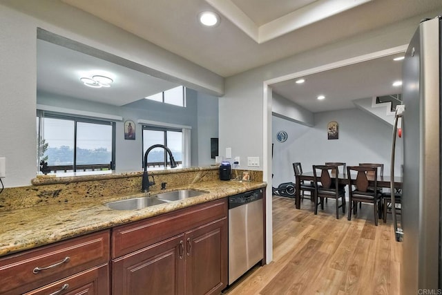 kitchen with light stone countertops, sink, light hardwood / wood-style flooring, and appliances with stainless steel finishes