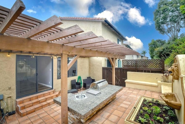 view of patio with area for grilling and a pergola