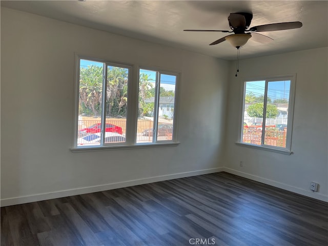 spare room featuring a healthy amount of sunlight, dark wood-type flooring, and ceiling fan