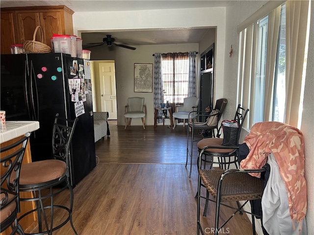 interior space featuring black refrigerator, ceiling fan, tile counters, and dark hardwood / wood-style floors