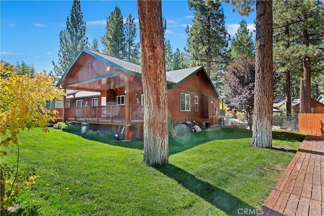 back of house featuring a wooden deck, ceiling fan, and a lawn