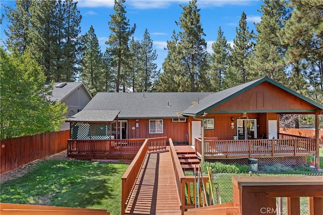 rear view of house with a wooden deck and a yard