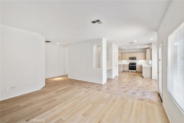 unfurnished living room with light hardwood / wood-style flooring and sink