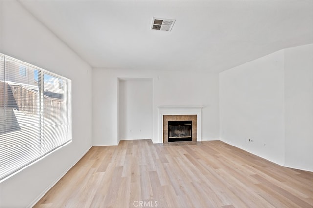 unfurnished living room with a tile fireplace and light hardwood / wood-style floors