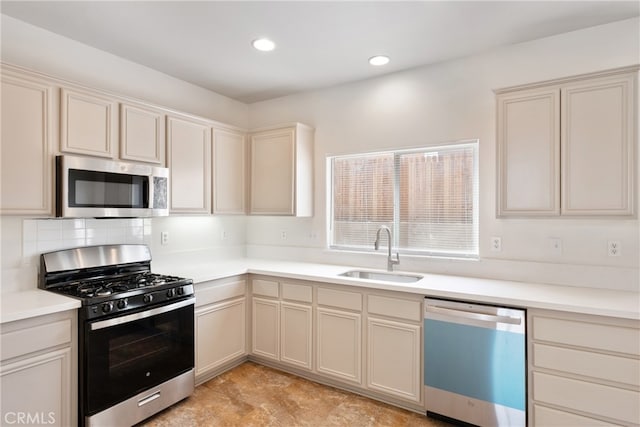 kitchen featuring stainless steel appliances, backsplash, cream cabinets, and sink