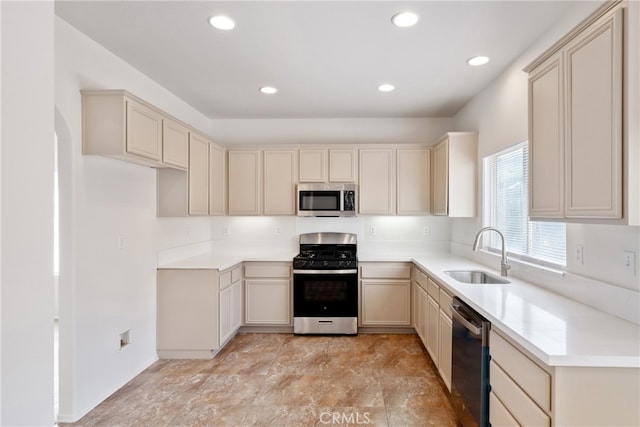 kitchen with stainless steel appliances, cream cabinetry, and sink