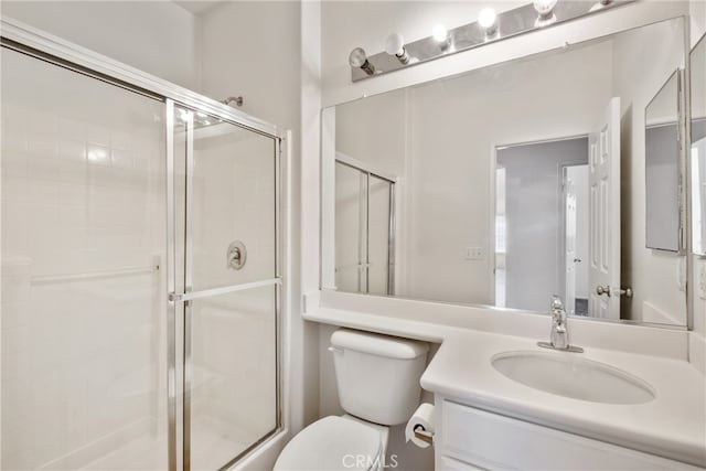 bathroom with vanity, toilet, and a shower with door